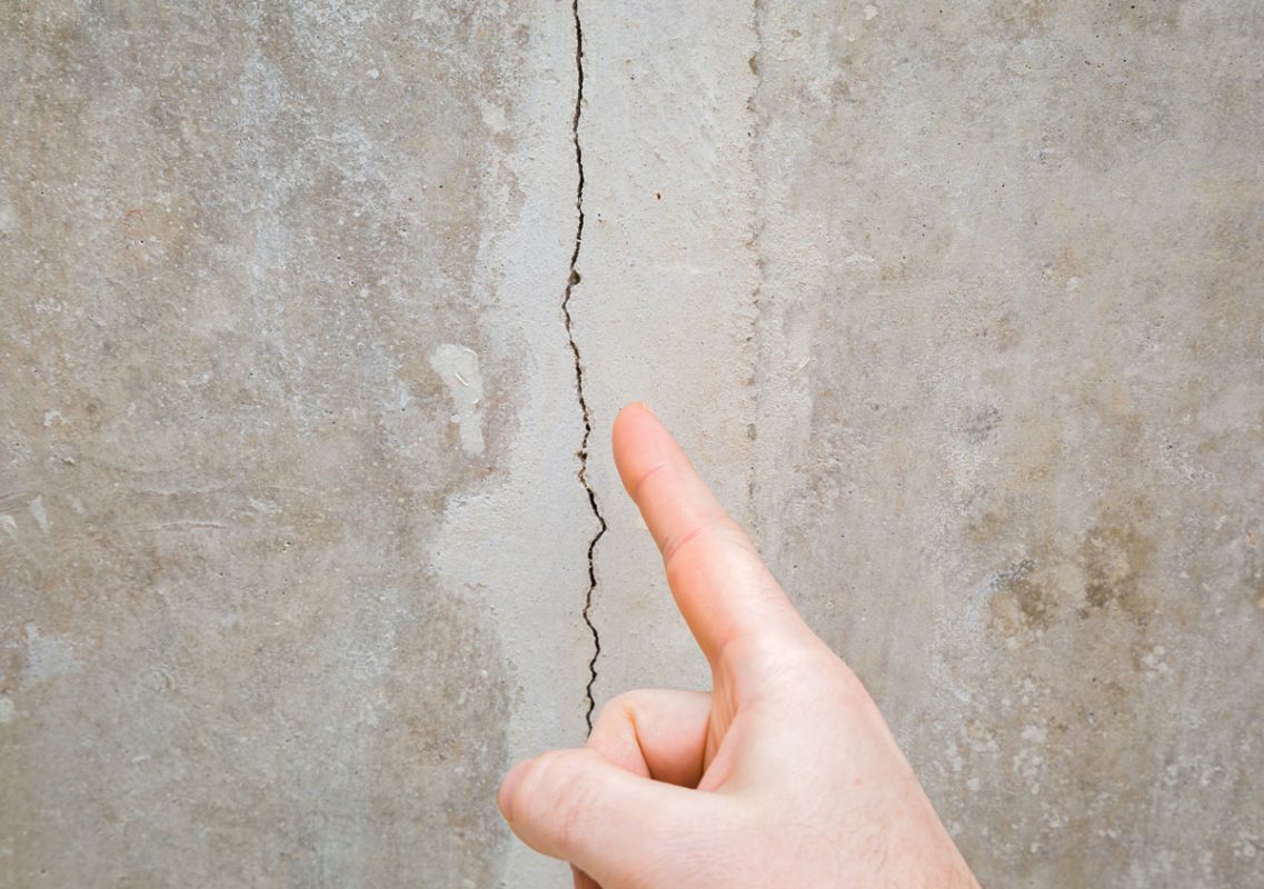Hand Pointing at a Crack in Stucco